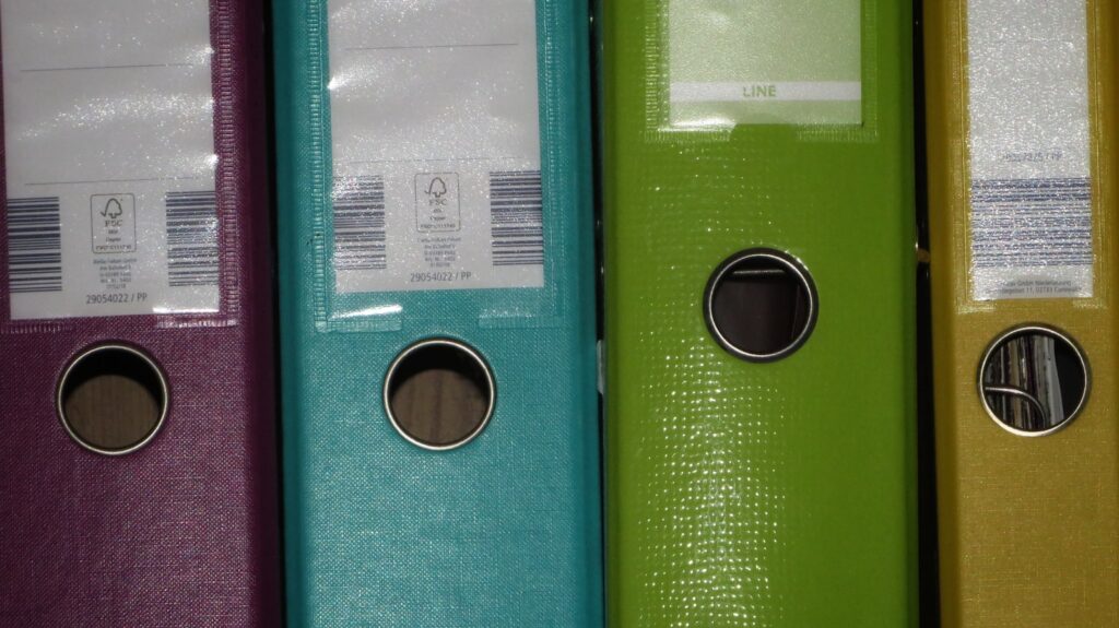 a row of colored binders on a shelf